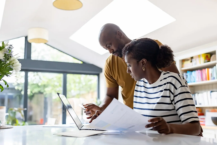 Couple looks at laptop and papers to file taxes