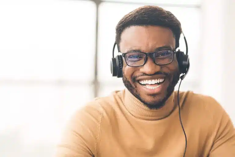 A smiling, helpful service desk representative in a turtleneck with a headset on.